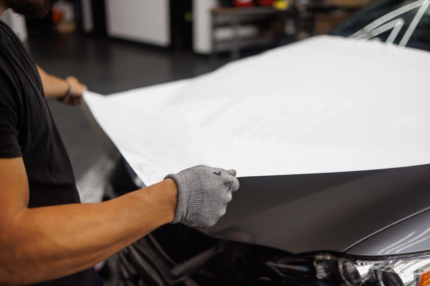 Installer applying a white vinyl wrap to a car hood